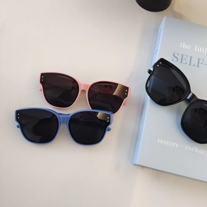Retro oversized kids sunglasses in pink, blue, and black colors on marble surface
