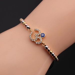 Close-up of beaded evil eye bracelet with Om charm and zircon inlay on wrist
