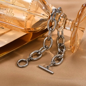 Macro detail of silver thick chain necklace with OT toggle clasp on a golden tray