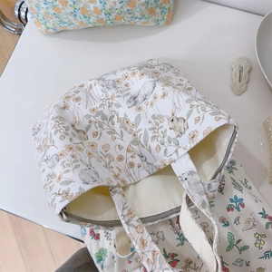 Detailed top view of cream cotton tote bags with floral rabbit and hedgehog prints