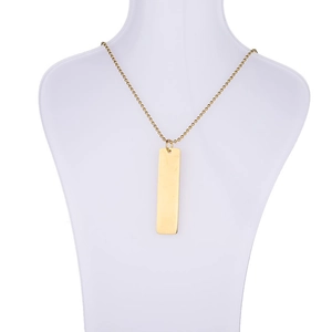 Detailed view of a gold rectangular bar pendant on a bead chain necklace on a bust