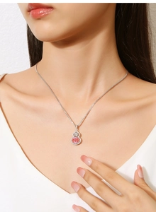 Macro detail of a S925 silver gourd pendant with a pink gemstone on a model neck