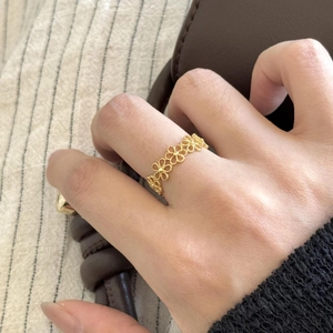 Detailed view of an elegant gold hollow flower ring worn by a model with a leather bag