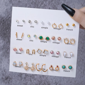 20 pairs of gold-tone geometric stud earrings with pearls and crystals on a white card