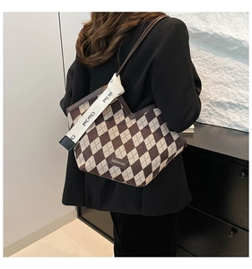 Detail of checkered canvas tote bag showing wide shoulder strap and woven pattern texture