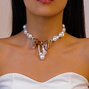 Detail of baroque pearl choker necklace featuring a leopard print resin bow pendant