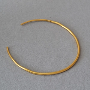 Minimalist gold plated irregular metal choker necklace on a soft grey fabric backdrop