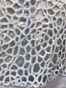 Gros plan sur le tissu en dentelle florale crochetée blanche avec doublure bleu clair
