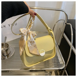 Close-up of yellow shoulder bag with metallic buckle and elegant silk scarf detail