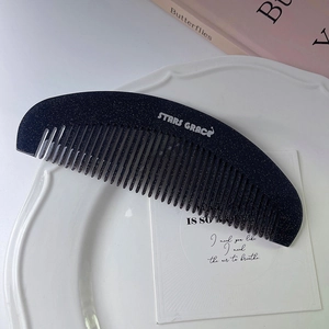 Detailansicht einer schwarzen Glitzer-Haarbürste mit Logo auf Keramikteller