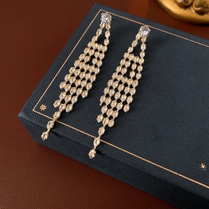 Close-up of gold plated drop earrings with sparkling zircons on a luxury gift box