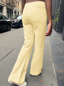 Detail view of light yellow high waisted flare yoga pants from a back perspective outdoor