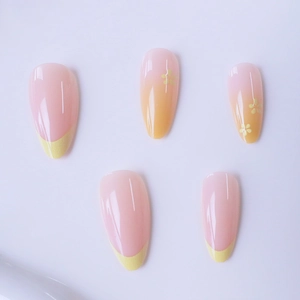 Almond press-on nails with pink to yellow gradient, French tips, and floral accents