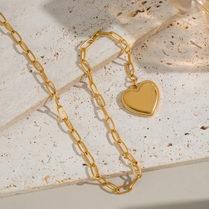Minimalist 18K gold plated heart pendant necklace on a natural textured stone surface