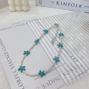 Detailed shot of white seed bead necklace with blue starfish pendants and S925 silver clasp