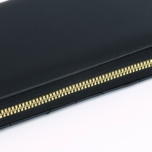 Macro shot of gold metal zipper teeth on premium black textured leather wallet detail