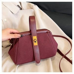 Detail of wine red shell bag showing matte suede texture and gold twist lock closure