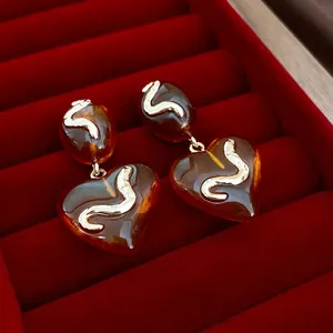 Elegant amber resin heart earrings with golden snake wave inlay on a red velvet box