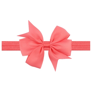 Close-up of coral pink grosgrain ribbon bow headband showing fine fabric texture