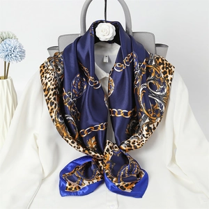 Detail of elegant silk scarf with gold chain and leopard print tied on a white shirt
