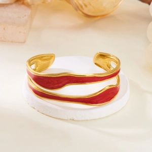 Vintage gold wavy cuff bracelet with deep red enamel inlay on stone display stand