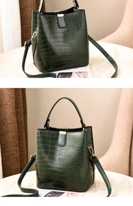 Detail of dark green crocodile texture bucket bag with gold metal buckle and straps
