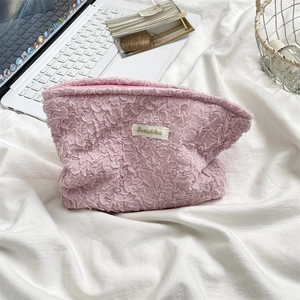 Detailed view of pink bubble textured makeup bag on a soft white linen background