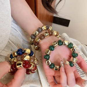 Detailed macro view of colorful glitter resin beads and gold geometric metal beads on bracelet