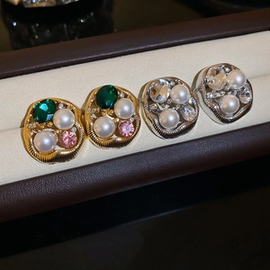 Macro detail of retro pearl and emerald crystal stud earrings in gold and silver finish