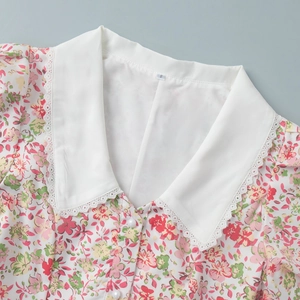 Close-up of floral print dress featuring a lace collar and white pearl button details