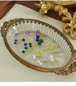 Close-up of colorful round bead stud earrings in purple, blue, and yellow on a gold tray
