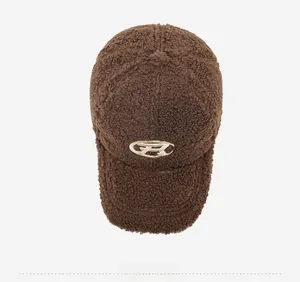 Close-up of thick teddy fleece texture and oval metal logo on the brown baseball cap