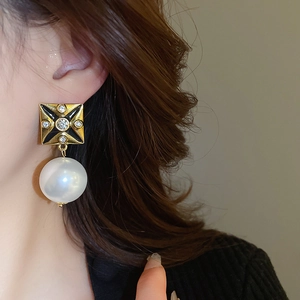 Close-up of model wearing vintage square stud earrings with rhinestones and pearl