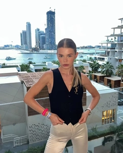 Détail d'un gilet noir chic à col en V avec une broche dorée et une coupe très ajustée