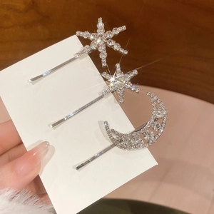 Detail of three-piece crystal hair clip set with star and moon designs in silver