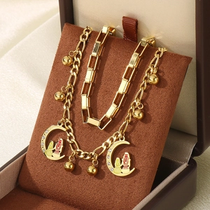 Gold layered heart and moon pendant bracelet set with small human charms on brown velvet