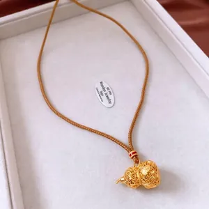 24k gold plated hollow gourd pendant necklace with intricate filigree on a silk background
