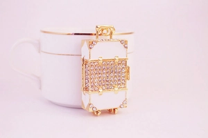 Close-up of golden suitcase keychain with sparkling rhinestones and detailed wheels