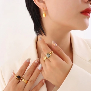 Elegant gold teardrop earrings and stone rings set on model with minimalist style