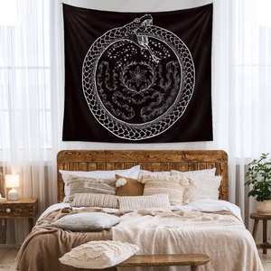Bohemian black wall tapestry with white Ouroboros symbol in a cozy bedroom setting