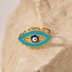 Macro shot of 18K gold plated evil eye ring with blue enamel on a natural stone base