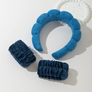 Close-up of sky blue sponge headband and matching navy plush wristbands on a tray