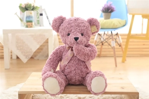 Detail view of pink teddy bear with rose-textured plush fur and gold-patterned ribbon bow