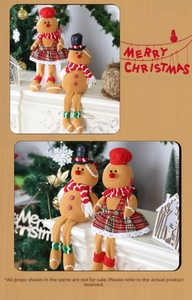 Detail of gingerbread man couple dolls with red plaid scarves on a festive fireplace