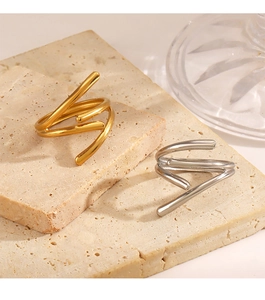 Detail of minimalist gold and silver spiral open rings on a textured beige stone base