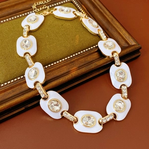 Détail du collier vintage doré avec maillons en émail blanc et cristaux brillants