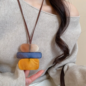 Detail of layered acrylic geometric pendant necklace in cream blue and orange tones
