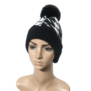 Classic black and white houndstooth knit beanie with a faux fur pompom on top