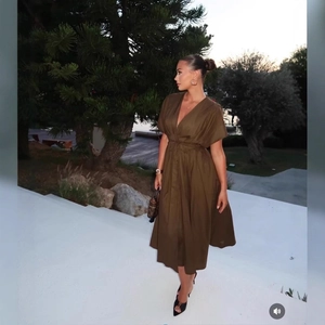 Robe midi plissée vert olive avec décolleté en V et ceinture sur des marches