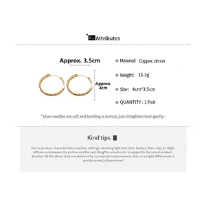Macro detail of 18k gold plated chain link hoop earrings with cubic zircon and silver needle